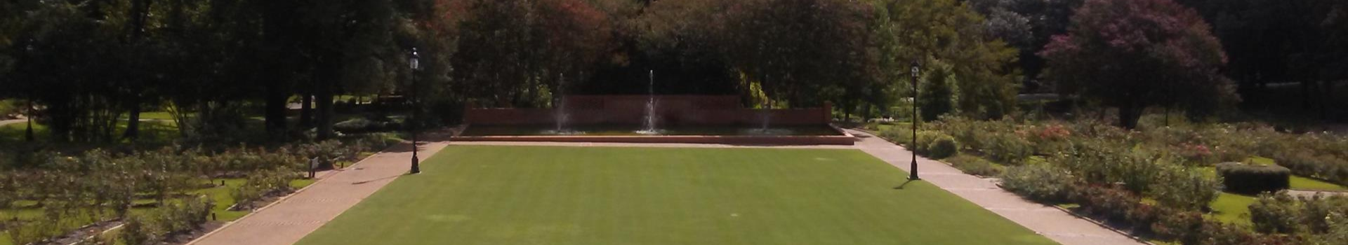 Empty grand lawn with a fountain at the end at teh Queen's Court int he Tyler Rose Garden