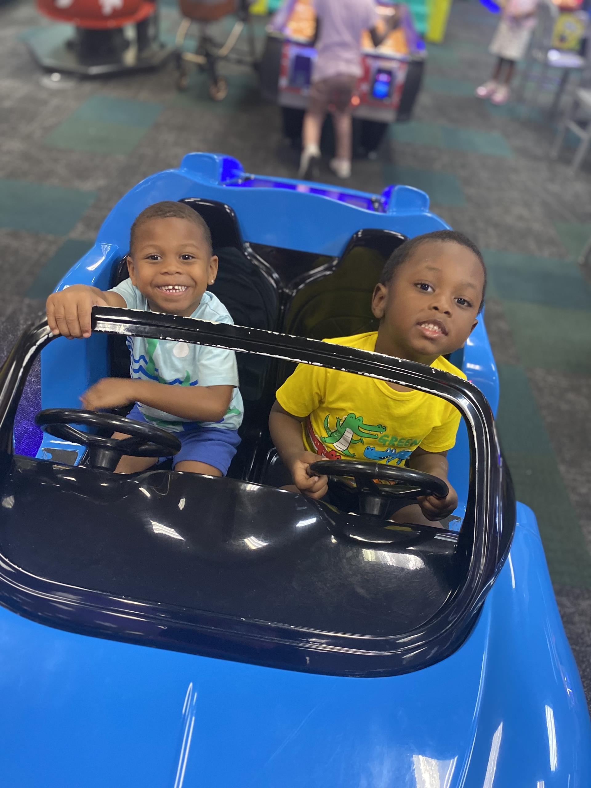 A picture of missing children Legend Sanford and Kannon O'Neal. The boys are seen sitting in a blue toy car and smiling. 